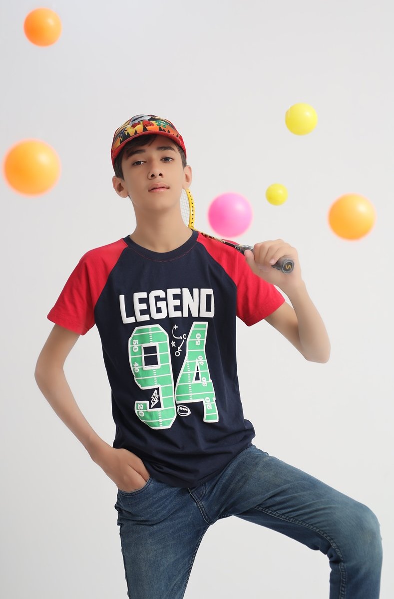 Boy in a navy blue and red Legend 94 cotton T-shirt with badminton racket and colourful balls