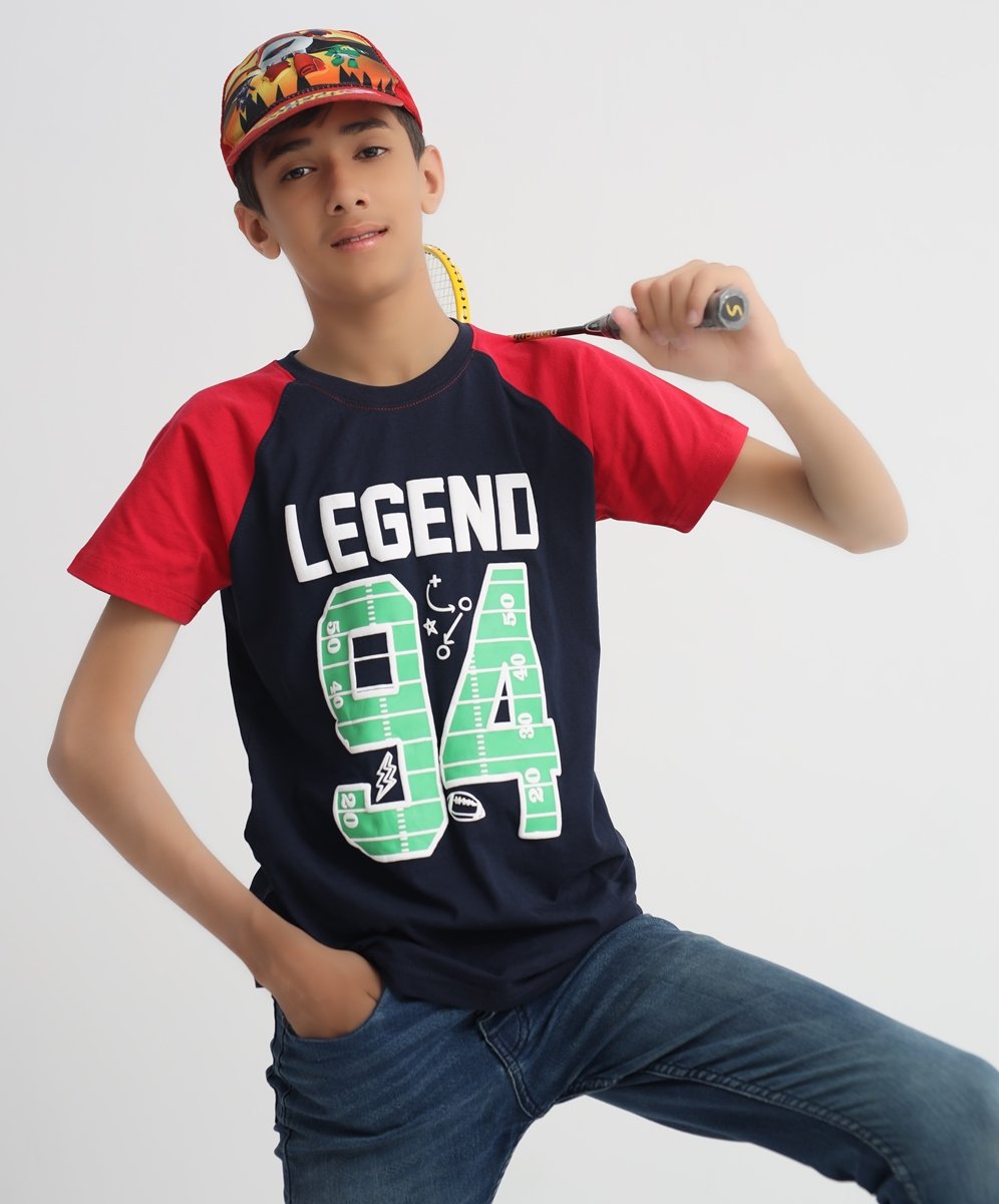 Boy wearing a navy and red Legend 94 graphic T-shirt while holding a badminton racket