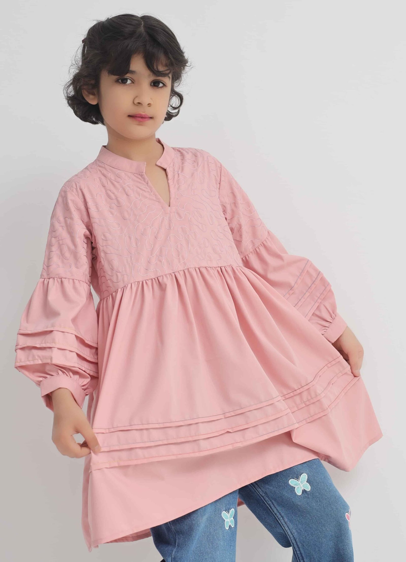 Girl wearing a pink embroidered frock with gathered sleeves